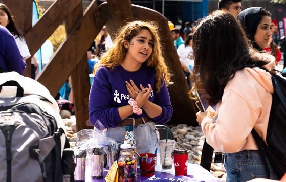 A student speaking at a table during a fair